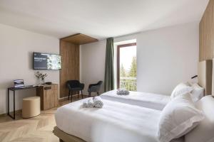 a hotel room with two beds and a television at B&B Hotel Passo Tre Croci Cortina in Cortina dʼAmpezzo