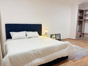 ein großes weißes Bett mit blauem Kopfteil in einem Schlafzimmer in der Unterkunft A Serene home away from home in Damba