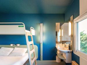 ein Schlafzimmer mit einem Etagenbett und einem Waschbecken in der Unterkunft ibis budget Mâcon Nord in Mâcon