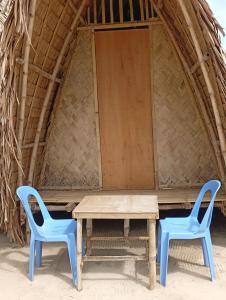 two blue chairs and a wooden table in front of a hut at El Hermosa Bice Camp in El Nido +6 photos