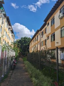 Ein Weg zwischen zwei Gebäuden neben einem Zaun in der Unterkunft Apto 2 quartos Grã Duquesa in Governador Valadares
