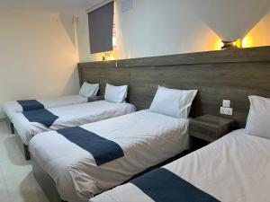 three beds in a room with white and blue sheets at Happy Beach Castel for Apartment قلعة شاطئ السعادة للشقق المفروشة in Aqaba