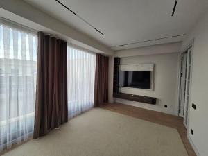 een woonkamer met een televisie en grote ramen bij Penthouse Nusha Apartments in Doesjanbe