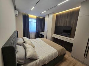 een slaapkamer met een groot bed en een tv aan de muur bij Penthouse Nusha Apartments in Doesjanbe