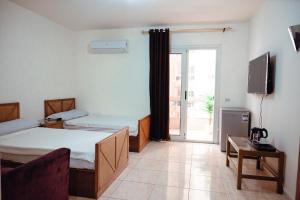a bedroom with two beds and a tv and a window at Smouha Hotel in Alexandria