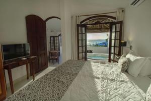 een slaapkamer met een bed, een televisie en een balkon bij Pousada Natureza in Morro de São Paulo