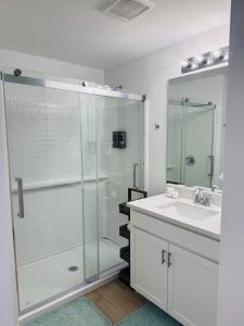 een badkamer met een glazen douche en een wastafel bij Blue Mantle Charlotte Hideaway in Port Charlotte