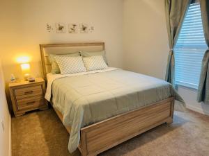 een slaapkamer met een bed, een nachtkastje en een raam bij Blue Mantle Charlotte Hideaway in Port Charlotte