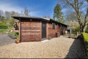 a wooden cabin with a door on a gravel yard at Piglets Place in Hythe
