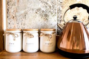 a tea kettle and three jars on a counter at Piglets Place in Hythe