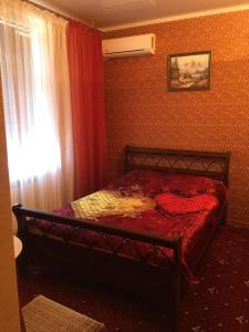 Schlafzimmer mit einem Bett mit roter Bettwäsche und einem Fenster in der Unterkunft Aparthotel "Lechebnaya" in Kasan