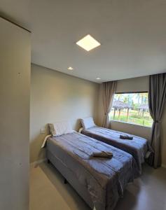 Maravilhosa Casa 5 Quartos-Reserva de Sauípe في كوستا دو ساويب: سريرين في غرفة بها نافذة