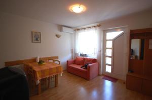 ein Wohnzimmer mit einem Tisch und einem roten Stuhl in der Unterkunft Apartment Bogoviciv in Malinska