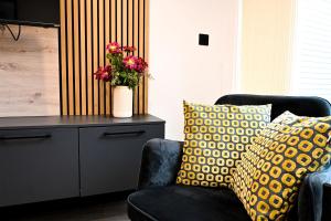 a living room with a chair and a vase with flowers at Laurie Grove in London