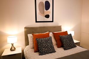 a bedroom with a bed with orange and black pillows at Laurie Grove in London