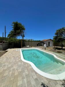 a swimming pool in a yard with a person standing next to it at Casa Fantástica in Guriri
