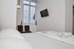 a white bedroom with two beds and a flat screen tv at Clarissa Guest House Cisarua Bandung in Sukaraja +29 photos