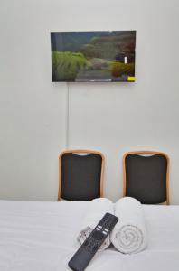 a remote control sitting on a bed with two chairs at Clarissa Guest House Cisarua Bandung in Sukaraja