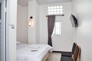 a bedroom with a bed and a chair and a window at Clarissa Guest House Cisarua Bandung in Sukaraja