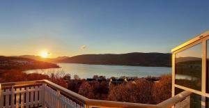 een uitzicht op een meer vanaf een terras met de zonsondergang bij Great apartment with extreme views in Tromsø