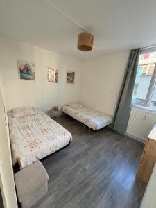 une chambre avec deux lits et une fenêtre dans l'établissement Appartement hyper-centre Stella, à Dunkerque 2 autres photos