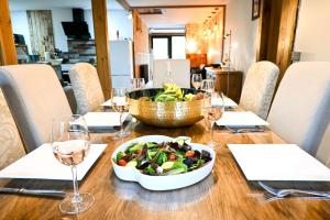 a wooden table with a bowl of salad and wine glasses at Pooh Corner in Hythe