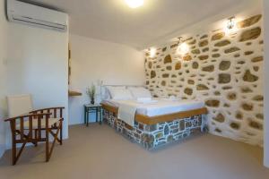 a bedroom with a bed and a stone wall at Casa Milos Aegean Suites in Alonnisos +115 photos