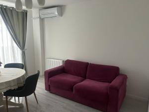 a purple couch in a living room with a table at Cozy Appartament in Floreşti +5 photos