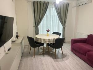 a living room with a table with chairs and a purple couch at Cozy Appartament in Floreşti