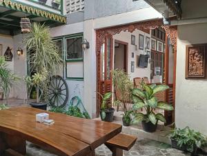 a wooden table in front of a house with plants at Omah Ndanu Homestay in Yogyakarta