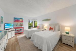 a bedroom with two beds and a flat screen tv at Blind Pass #E209 in Sanibel +51 photos