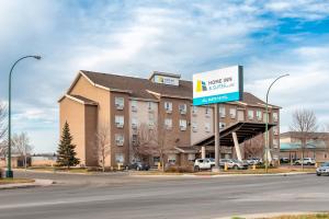 a large building with a sign for a hotel at Home Inn & Suites Regina East in Regina
