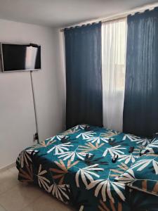 a bedroom with a bed and a window with blue curtains at Apartamento cerca del aeropuerto in Bogotá
