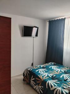 a bedroom with a bed and a flat screen tv at Apartamento cerca del aeropuerto in Bogotá
