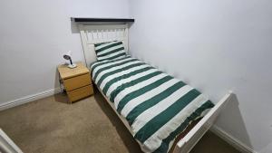 ein Bett mit einem grün-weiß gestreiften Kissen darauf in der Unterkunft Value Stay Comfortable Rooms Windsor Legoland Heathrow in Windsor