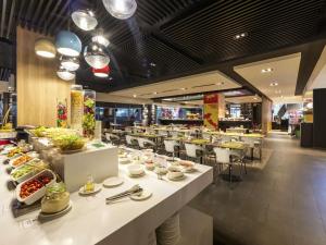 a restaurant with white tables and chairs with food at Ibis Saigon Airport in Ho Chi Minh City