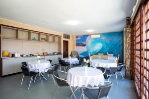 a dining room with tables and chairs and a painting at POUSADA JURERE in Florianópolis