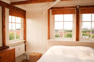 een slaapkamer met een wit bed en ramen bij Het Dakhuis in Harlingen