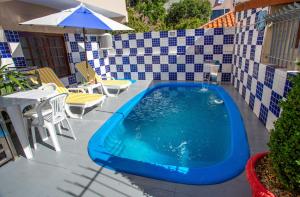 a swimming pool on a patio with a table and umbrella at POUSADA JURERE in Florianópolis