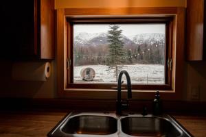 un lavello da cucina davanti a una finestra con vista invernale di Barrel sauna & Northern lights getaway a Wasilla Altre 27 foto