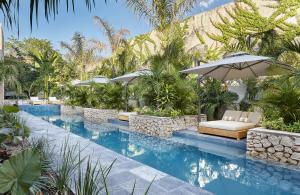 een zwembad in het resort met stoelen en parasols bij Ontico Urban Design Hotel in Mérida