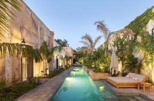 a swimming pool next to a building with an umbrella at Ontico Urban Design Hotel in Mérida