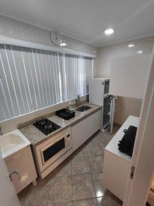 eine Küche mit Herd und weißem Kühlschrank in der Unterkunft Studio pé na areia Pereque - Açu in Ubatuba