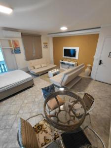 ein großes Wohnzimmer mit einem Sofa und einem TV in der Unterkunft Studio pé na areia Pereque - Açu in Ubatuba