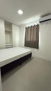 een witte kamer met een bed en een gordijn bij Apartamento Res Ilha Bella in Passo De Torres