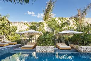 een zwembad met stoelen en parasols naast een resort bij Ontico Urban Design Hotel in Mérida