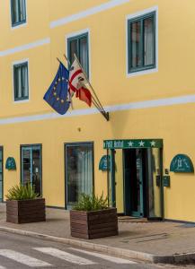 um edifício amarelo com duas bandeiras à frente em New Petit Hotel em Tempio Pausania