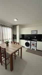 een grote keuken met een houten tafel en stoelen bij Apartamento Res Ilha Bella in Passo De Torres
