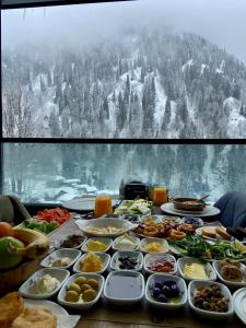 un tavolo sormontato da piatti di cibo con una montagna coperta di neve di Ayder Villa de Pelit Hotel ad Ayder Yaylasi