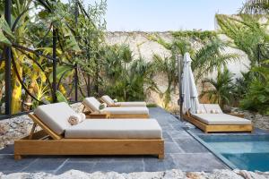 vier ligstoelen en een parasol naast een zwembad bij Ontico Urban Design Hotel in Mérida +77 foto's